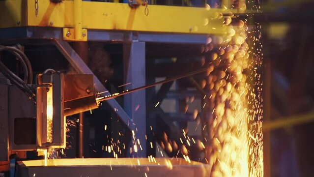 Bright yellow and orange sparks a splashing and flying from the furnace at modern steel manufacture plant. Metal cast in the foundry, hot liquid steel. Metallurgy. close up, slow motion