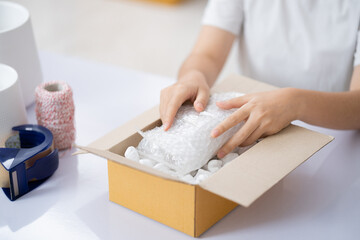 Small business entrepreneur woman packing product in mailing box for shipping from online store. Business online shipping and delivery concept.