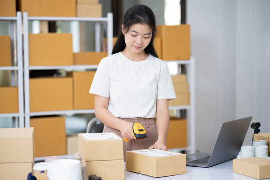 Young business online woman scanning package label with barcode reader at storehouse.