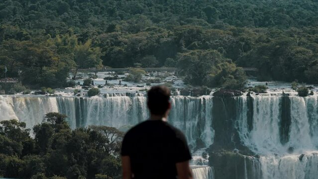 Man Looking At The Scenic Iguazu Falls Of Brazil And Argentina - Medium Shot