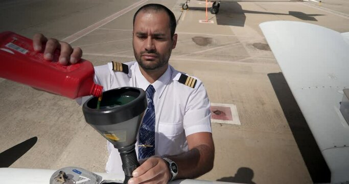 A pilot adds oil to the engine of his plane using a funne
