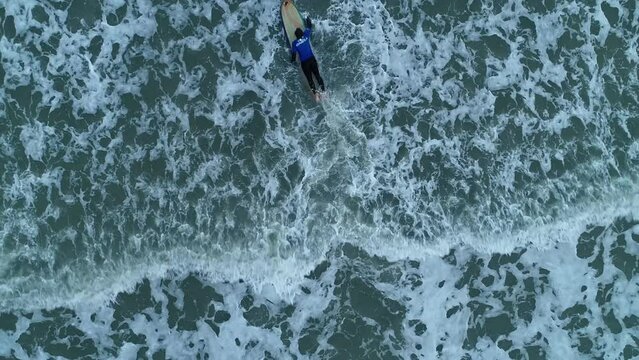 Drone footage of a surfer swim on his surfboard into the North Sea in Blankenberge town, Belgium
