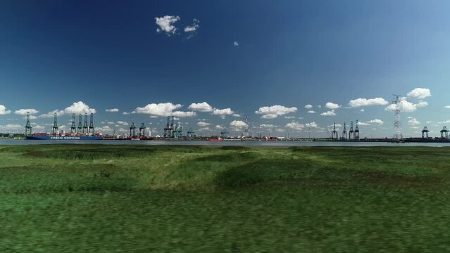Drone flying over green field in Doel village, with the Port of Antwerp in the background, Belgium