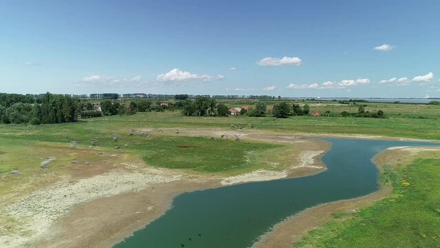 Drone footage of a small flock of birds flying over a lake in green field in Doel village, Belgium