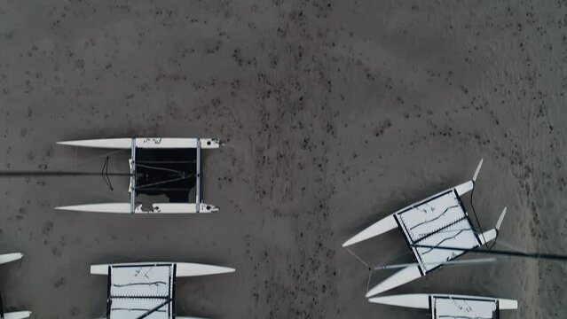 Drone shot of surfers running towards sea between catamarans on the beach in Blankenberge, Belgium