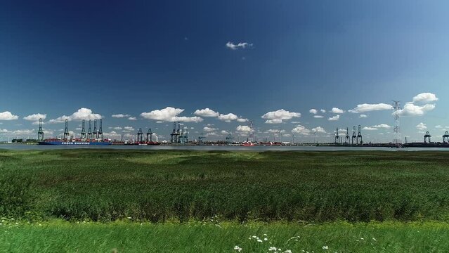 Drone flying over green field in Doel village, with the Port of Antwerp in the background, Belgium