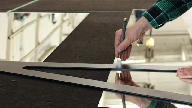 A professional glazier cuts glass by hand, glass factory