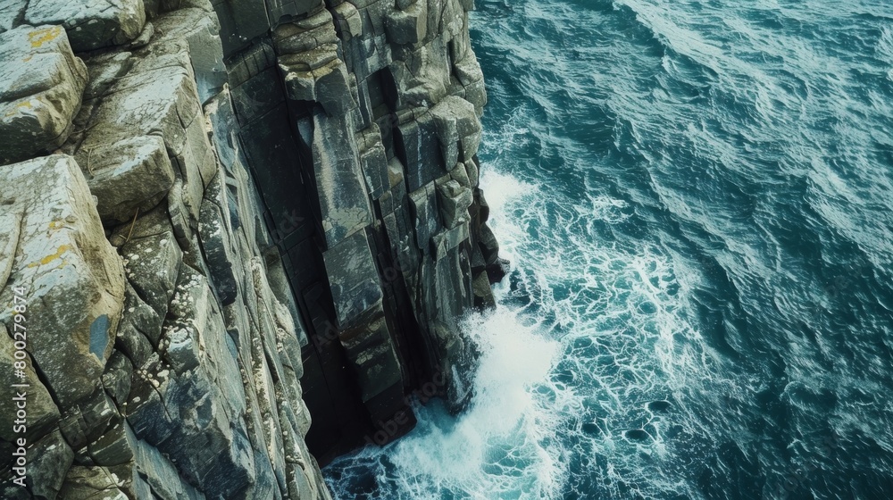 Poster the aerial view shows the vast expanse of the ocean with towering cliffs along the coastline. waves 