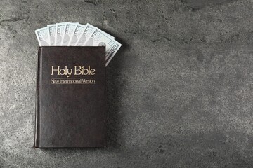 Holy Bible and money on grey table, top view. Space for text