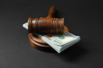 Law gavel with stack of dollars on black table