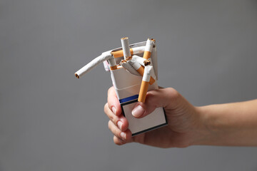 Stop smoking. Woman holding pack with broken cigarettes on grey background, closeup