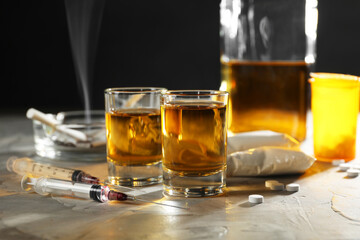 Alcohol and drug addiction. Whiskey in glasses, syringes, pills and cocaine on grey table