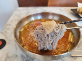 using chopsticks to eat from a bowl of noodles