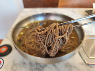 using chopsticks to eat from a bowl of noodles