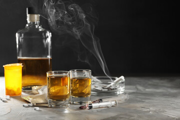 Alcohol and drug addiction. Whiskey in glasses, syringes, pills and cocaine on grey table, space...