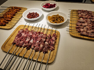 skewers with raw meat on wooden plate