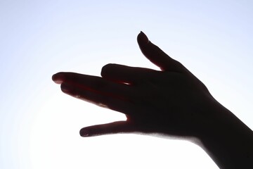 Shadow puppet. Woman making hand gesture like dog on light background, closeup