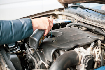 A man pours motor oil into a car engine. Changing and adding oil, car maintenance