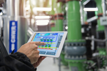 person holding a tablet computer on chiller Plant background. Industrial interior chiller and...
