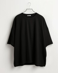 Black t-shirt hanging on a white hanger against a white wall