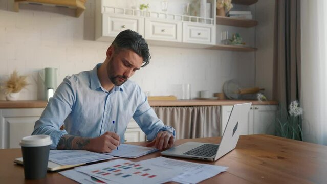 Serious man working with documents. Financial analyst businessman checking corporate financial papers with graphs diagrams, preparing audit report. Home office, freelance, paperwork, concept. - Powered by Adobe