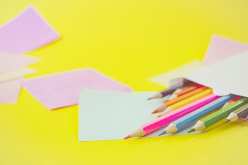 Colored pencils and stickers on a yellow background, for drawing school supplies