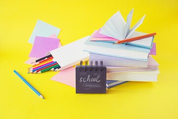 back to school with colorful books and pencils on yellow background,  school supplies