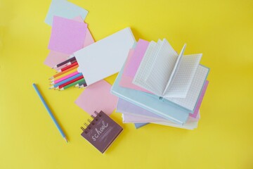 back to school with colorful books and pencils on yellow background,  school supplies