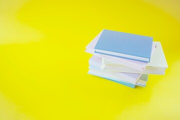 Stack of colorful books on a yellow background. Back to school.