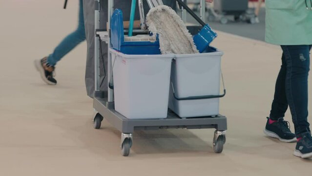 Janitorial cart with mops and cleaning supplies in facility corridor