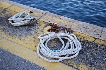 coil of white rope on the quay side with water in the background