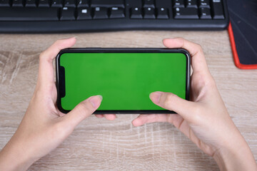 hand holding smart phone like play games with greenscreen and isolated on table
