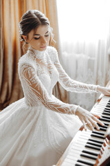 A woman in a wedding dress is playing the piano. The dress is white and has a long train. The woman...