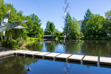 a beautiful spring landscape in the Sculpture Garden at New Orleans City Park with a lake, lush green trees, grass and plants, sculptures, people and blue sky in New Orleans Louisiana USA