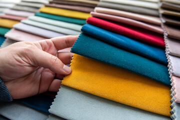 hand chooses fabrics textile from palette for repair sofa or chairs or any upholstered furniture
