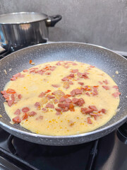 an omelet with sausage is fried in a pan