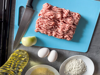 Fresh minced meat from various meats with oil, flour, egg, onion on the kitchen table