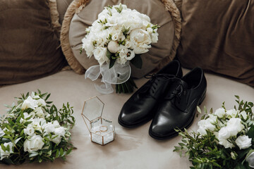 A black shoe and a white bouquet of flowers are displayed on a couch. The flowers are arranged in a...