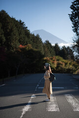 Tanuki Lake delight, Asian woman in Tokyo's urban landscape near Mount Fuji, navigating crosswalks and markets, creates a happy portrait in casual dress amid bustling city life.
