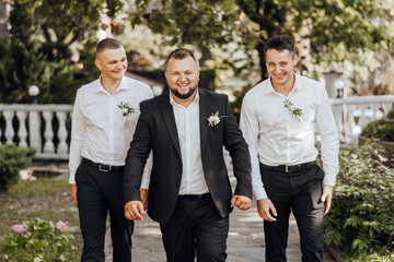 Three men in suits and ties walking down a path. One of the men is wearing a flower in his lapel