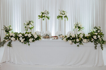 A table with white table cloth and white flowers on it. The table is set for a special occasion