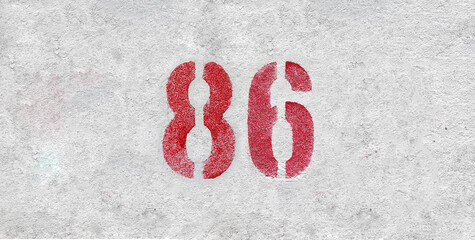 Red Number 86 on the white wall. Spray paint.