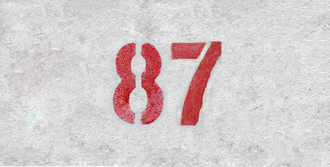 Red Number 87 on the white wall. Spray paint.