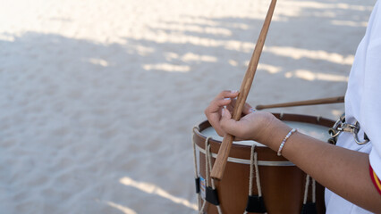 Close-up of a girl's hands playing a percussion musical instrument with sticks, a drum outdoors