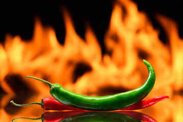 red and green chili peppers, on a background of burning fire, flames on a black background, hot and...