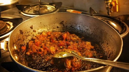 Traditional way of preparing indian masala for curry using gas pan. Picture of traditional India cuisine made of fresh ingredients in kitchen during dinner.