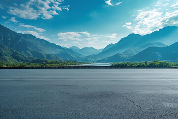 Empty asphalt under a blue sky and rolling mountains in the distance