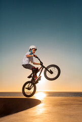 Naklejka premium A teenager BMX Racing Rider performs tricks in a skate park on a pump track.