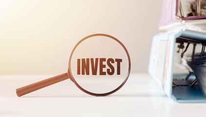 A magnifying glass highlighting the concept of investment against a backdrop of financial papers.