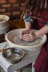 a women creats a vase from clay on a pottery wheel in a pottery 